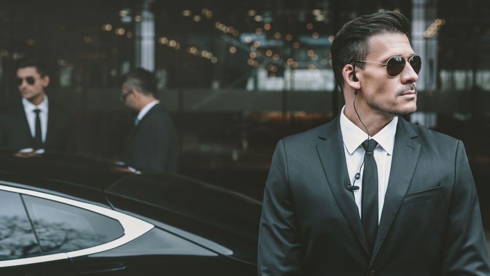 Executive protection agents around a principal entering a luxury vehicle